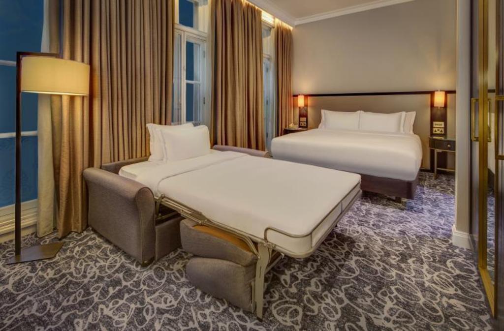 Hilton London Euston 침대·펼친 소파베드와 창문이 보이는 객실 내부 예시