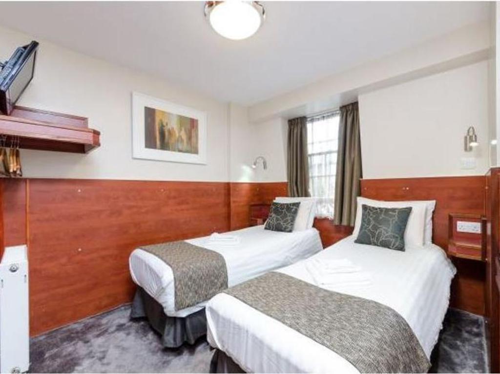 Wardonia Hotel Kings Cross 두 침대·창문·벽면 선반이 보이는 객실 내부 예시