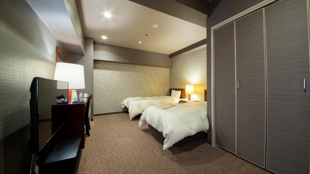 Grey leaf-pattern wall, twin beds, desk and TV