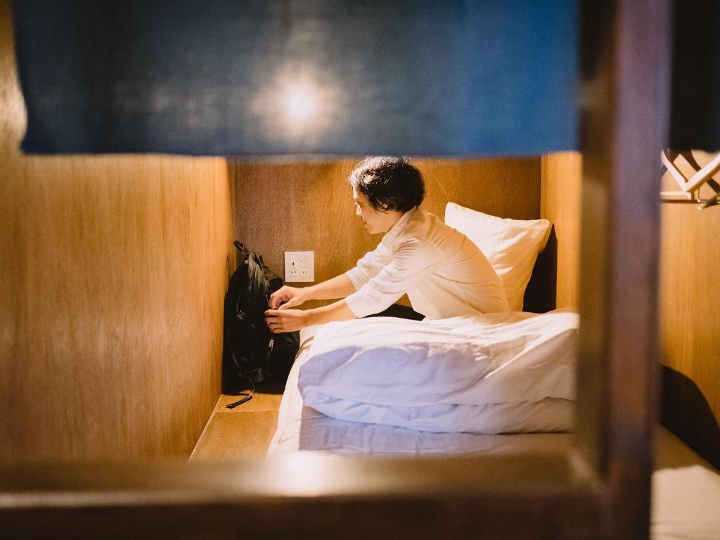 목재로 나눈 침상과 투숙 예시 인물이 보이는 히토야도 도미토리
