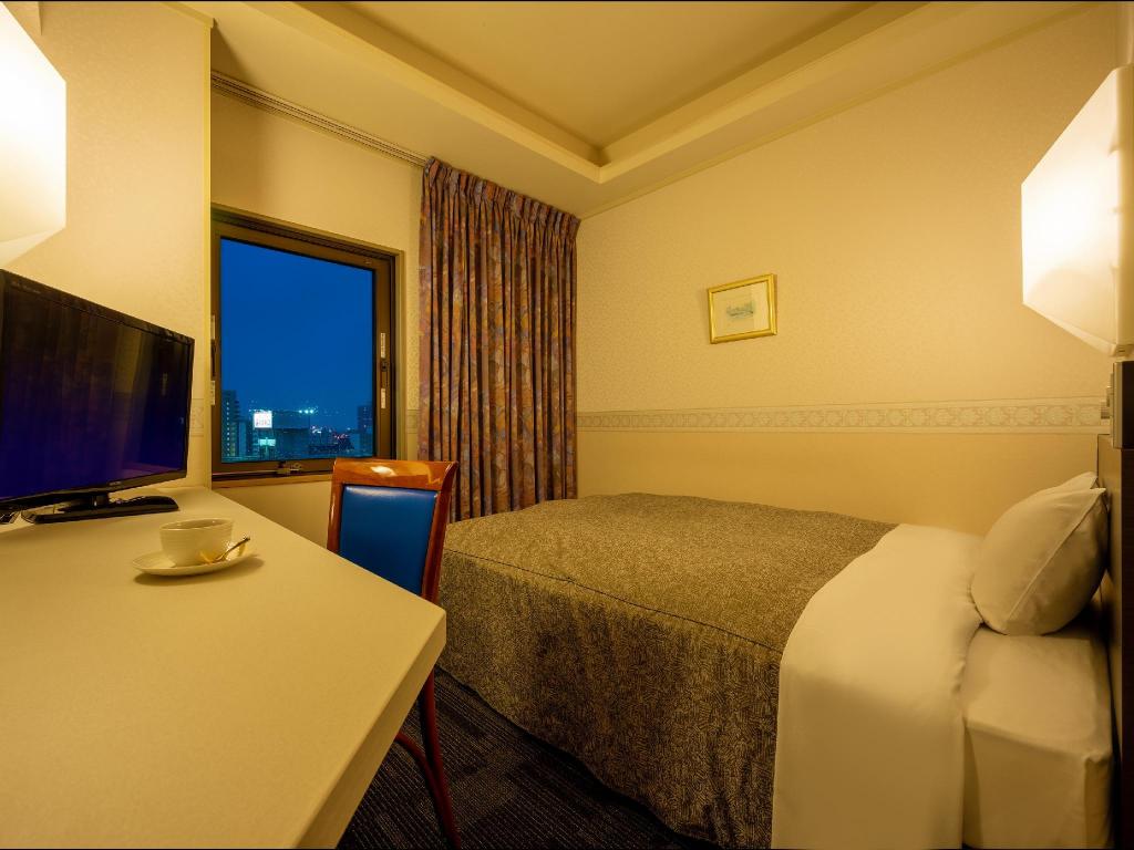 Blue chair, desk by the window and brown-toned bedcover