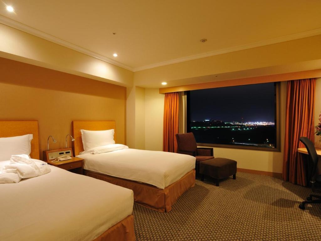 Hilton Tokyo Narita Airport 객실 내부: 두 침대·창가 의자·실내 이동 공간