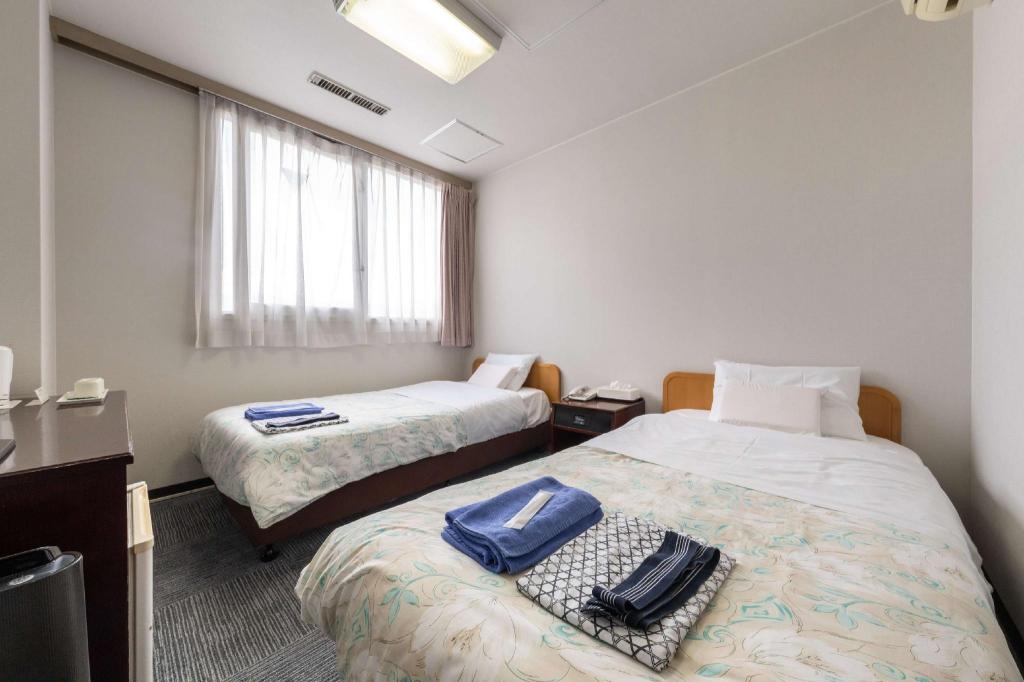 Two beds with floral bedding beside a window