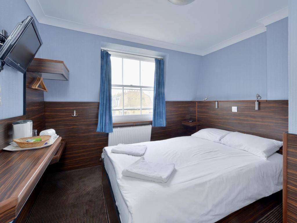Crestfield Hotel 침대·벽면 TV·파란 커튼이 보이는 객실 내부 예시