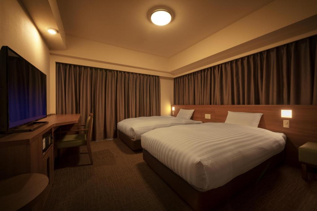 Twin beds, square reading lamps and brown curtains