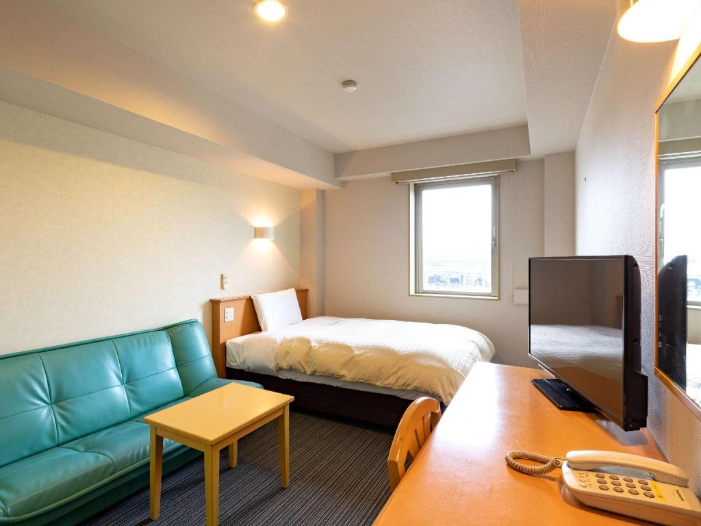 A bed, green sofa and wood desk