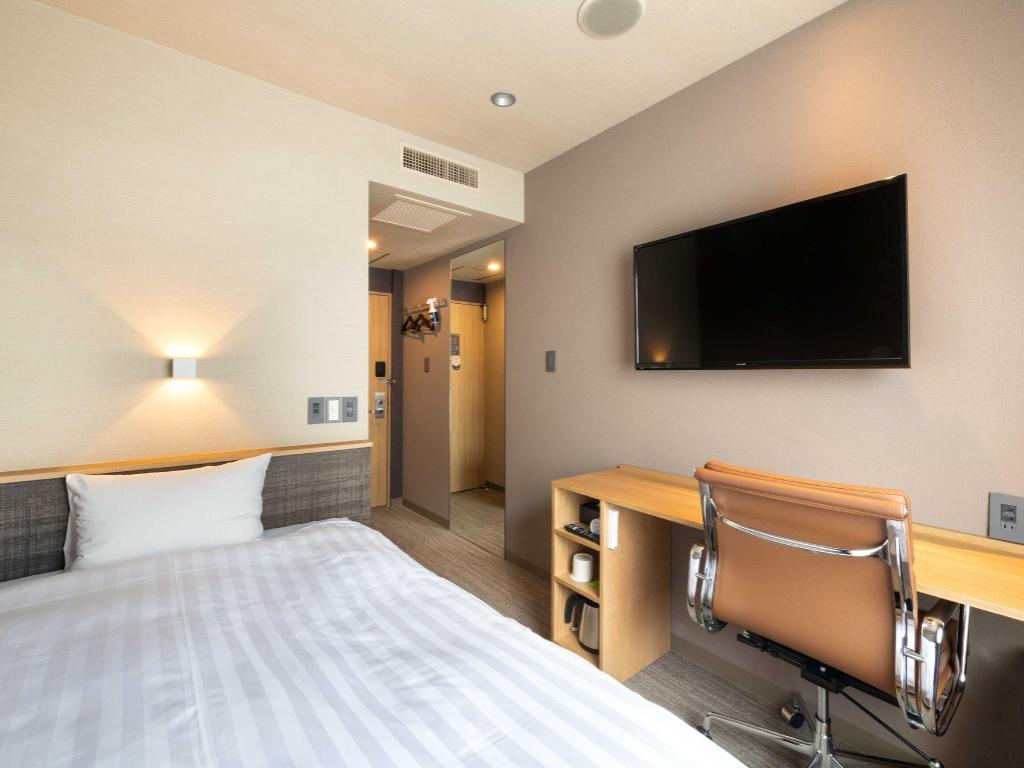 침대와 긴책상, 갈색의자·벽걸이TV가 보이는 EN HOTEL 하마마쓰 객실예시
