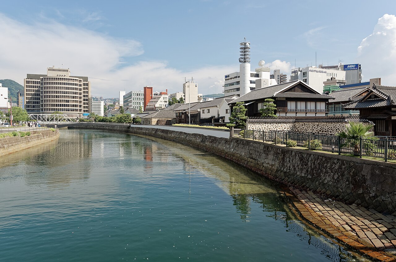 Restored Dejima trading-post buildings beside the river, photographed from Tamae Bridge in2024