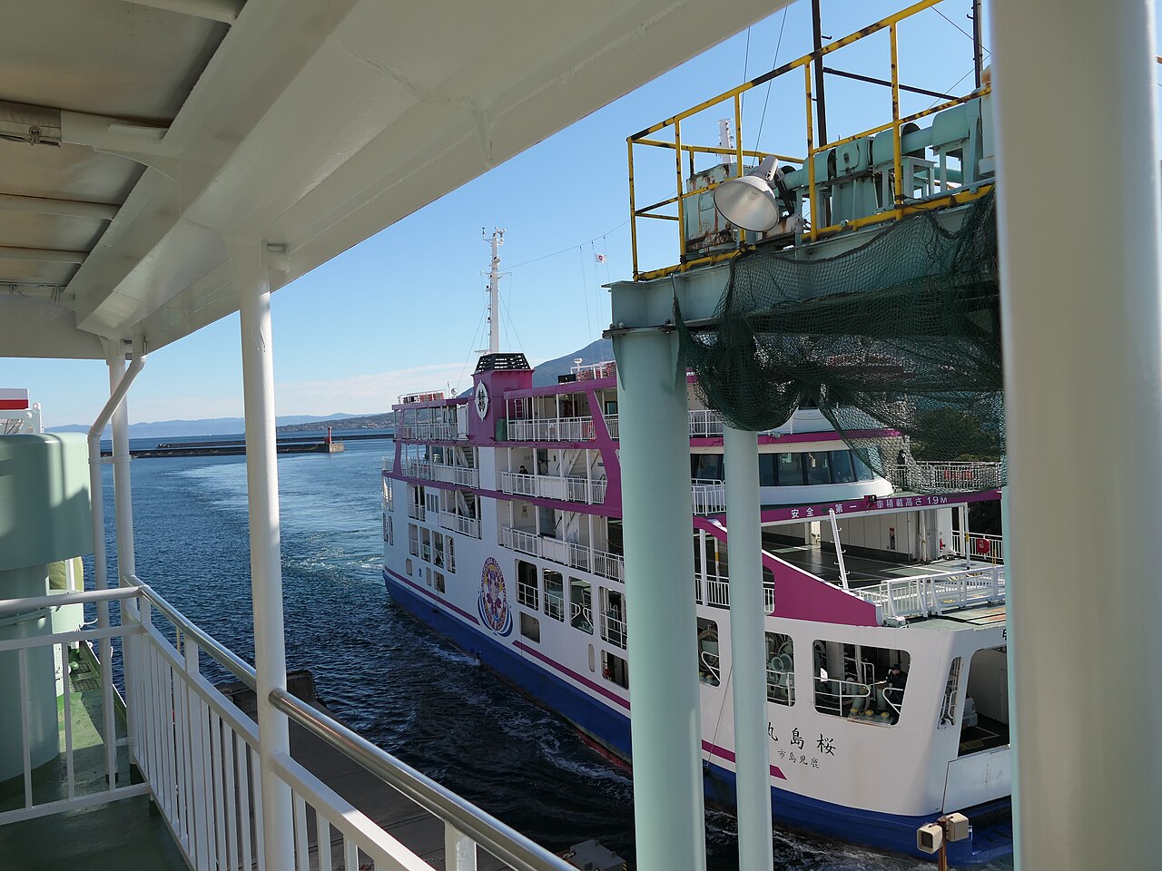 Another Sakurajima ferry seen past deck railings in January 2026