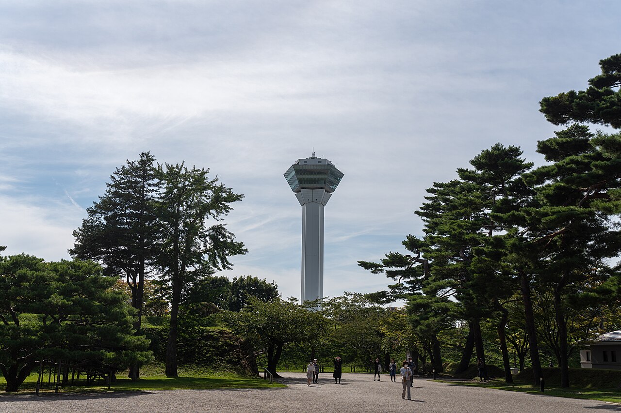 Goryokaku Tower beyond park trees and a gravel path in 2022
