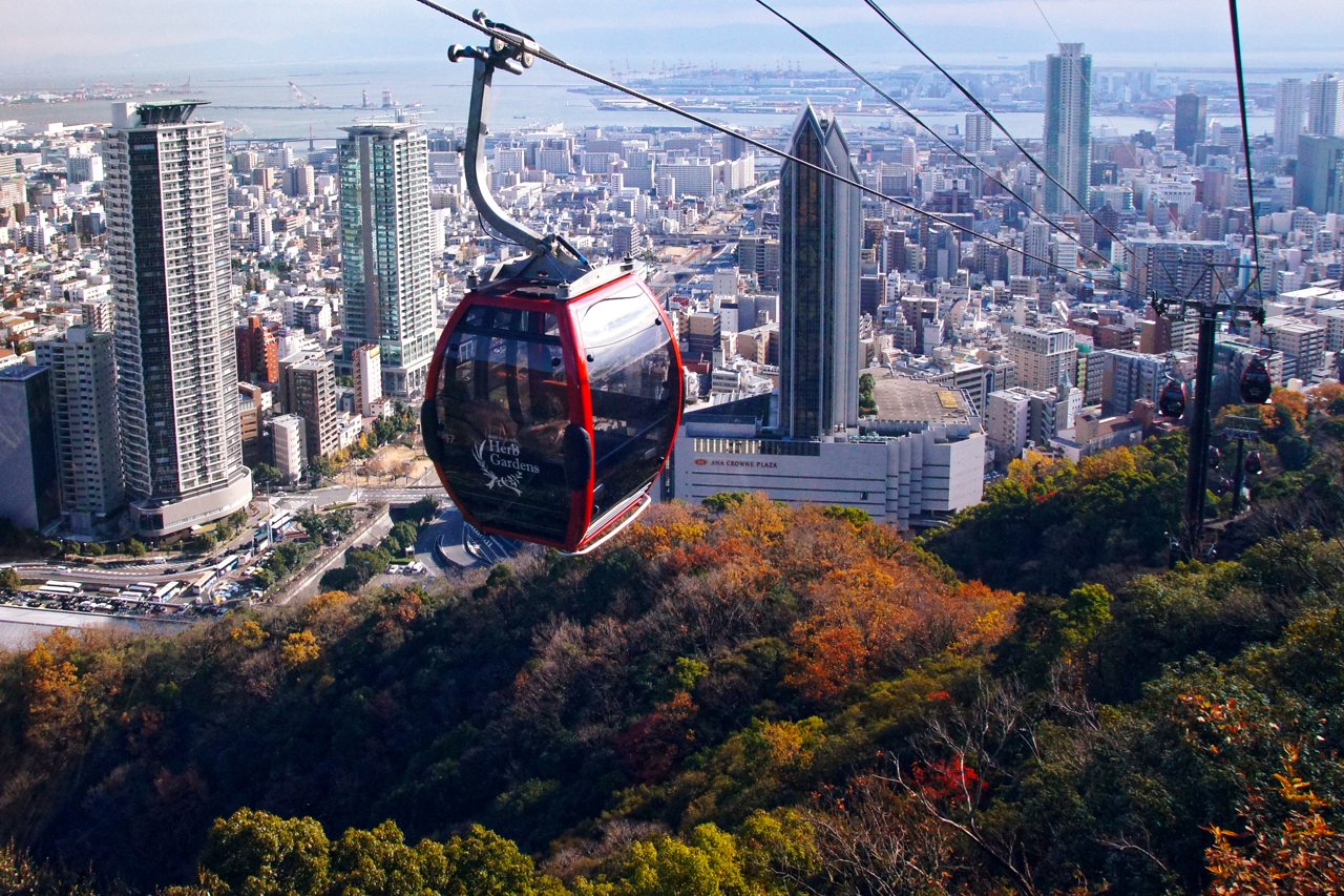 고베 시내와 항구를 배경으로 운행 중인 붉은 누노비키 로프웨이 곤돌라
