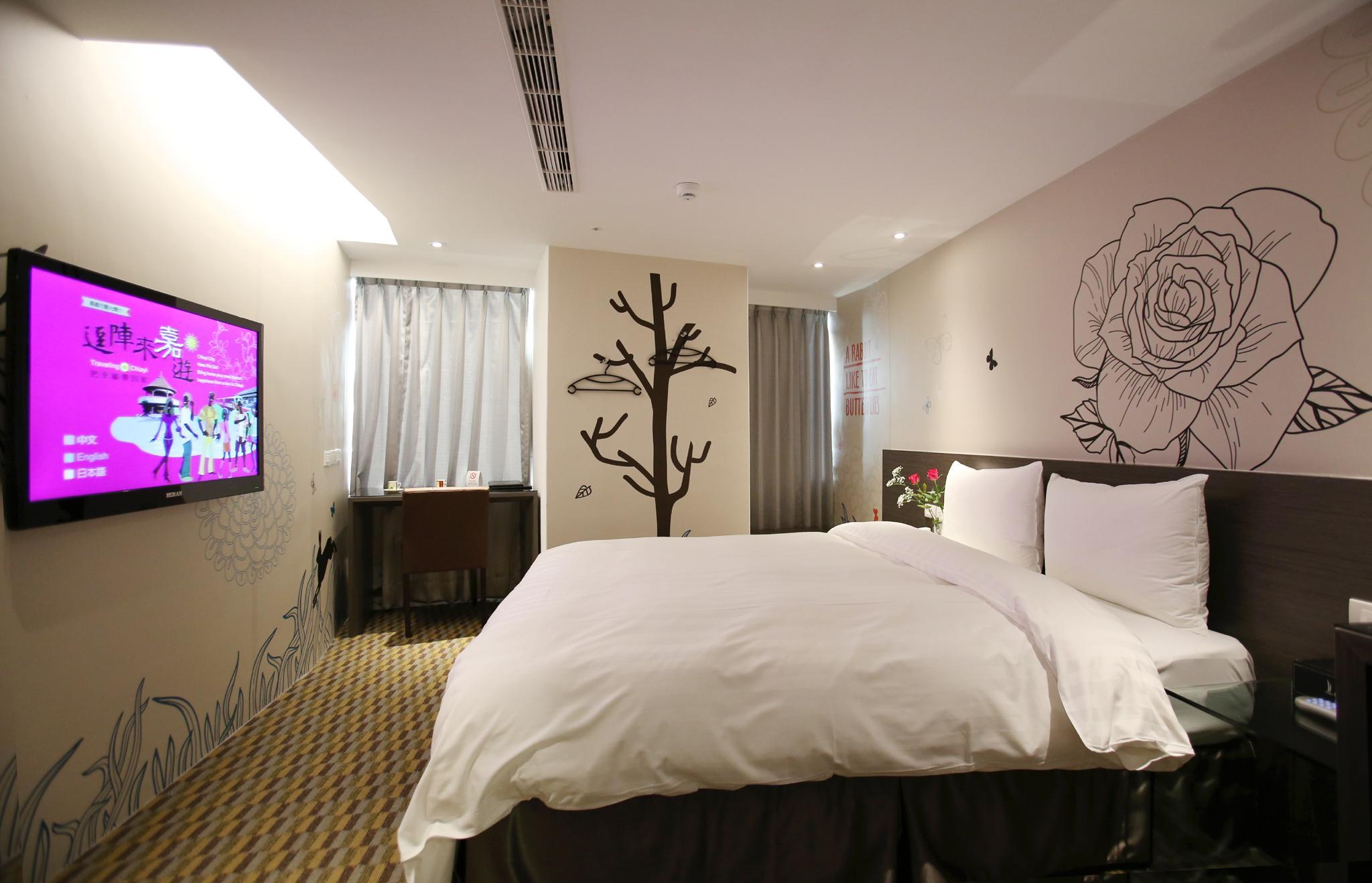 Chiayi Look Hotel: A room with a large bed, television, desk, curtained windows and floral artwork
