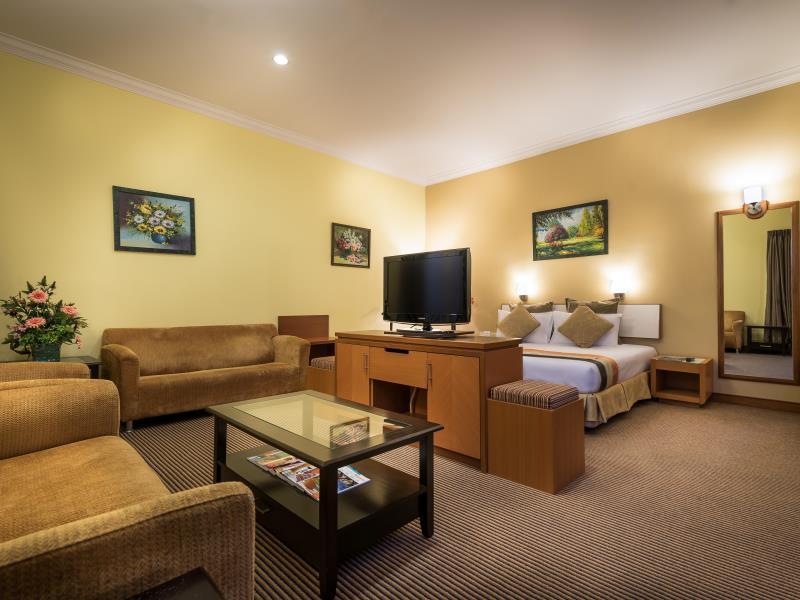 Hotel Sentral Kuala Lumpur: 침대·소파·유리 테이블과 TV 칸막이가 보이는 객실