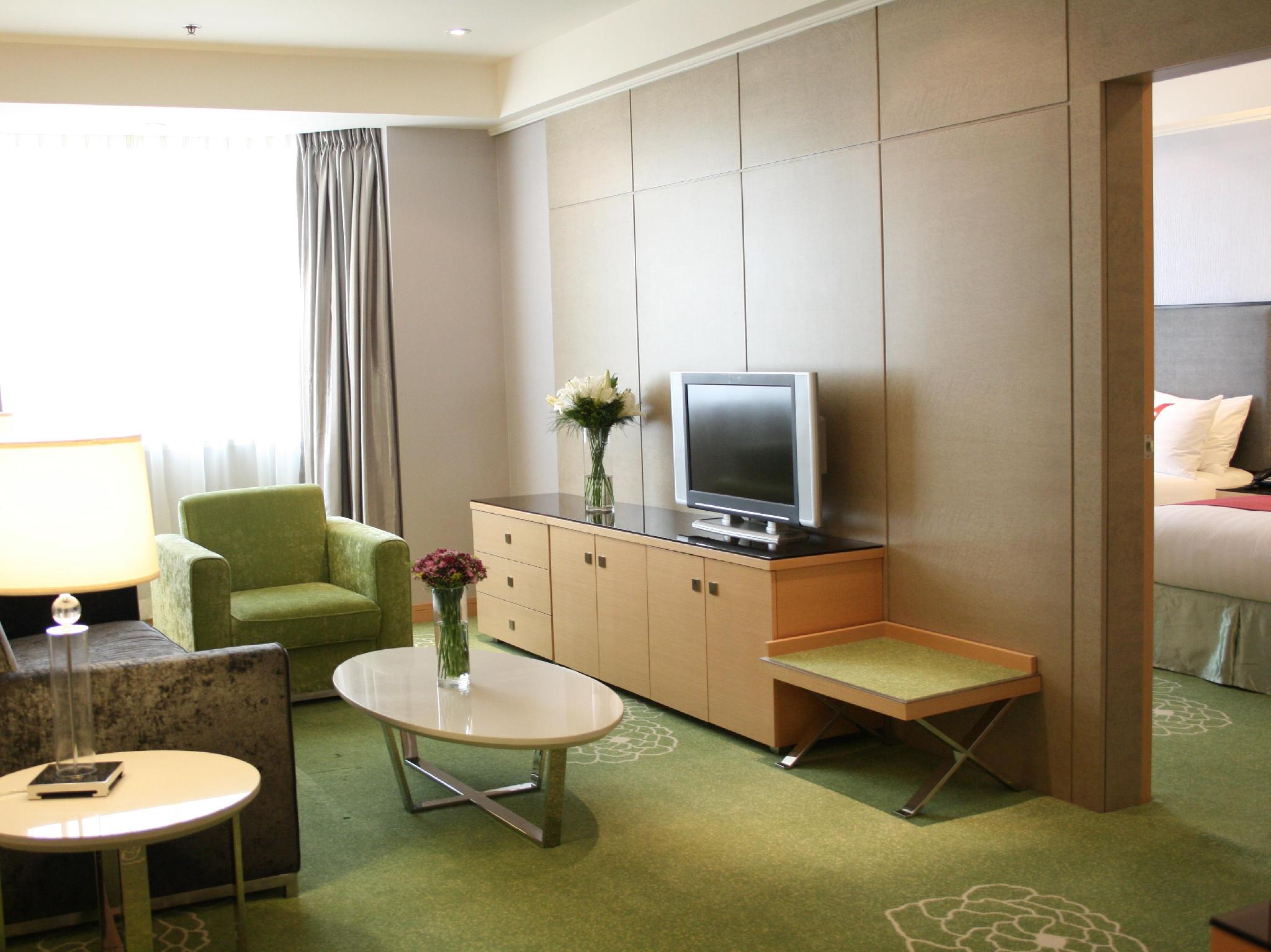 Holiday Inn Macau 공급사 객실 사진: 소파·테이블·TV가 있는 생활 공간과 문 너머 침실