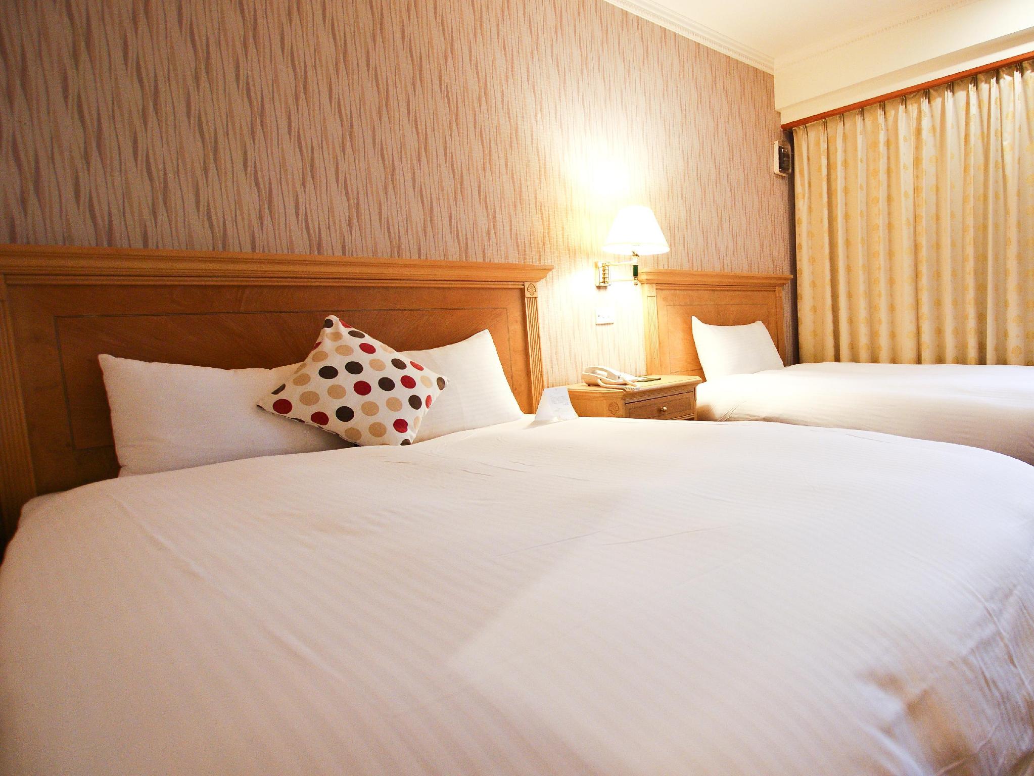Cambridge Tainan Hotel: Guestroom with two beds, a wooden headboard and patterned cushions
