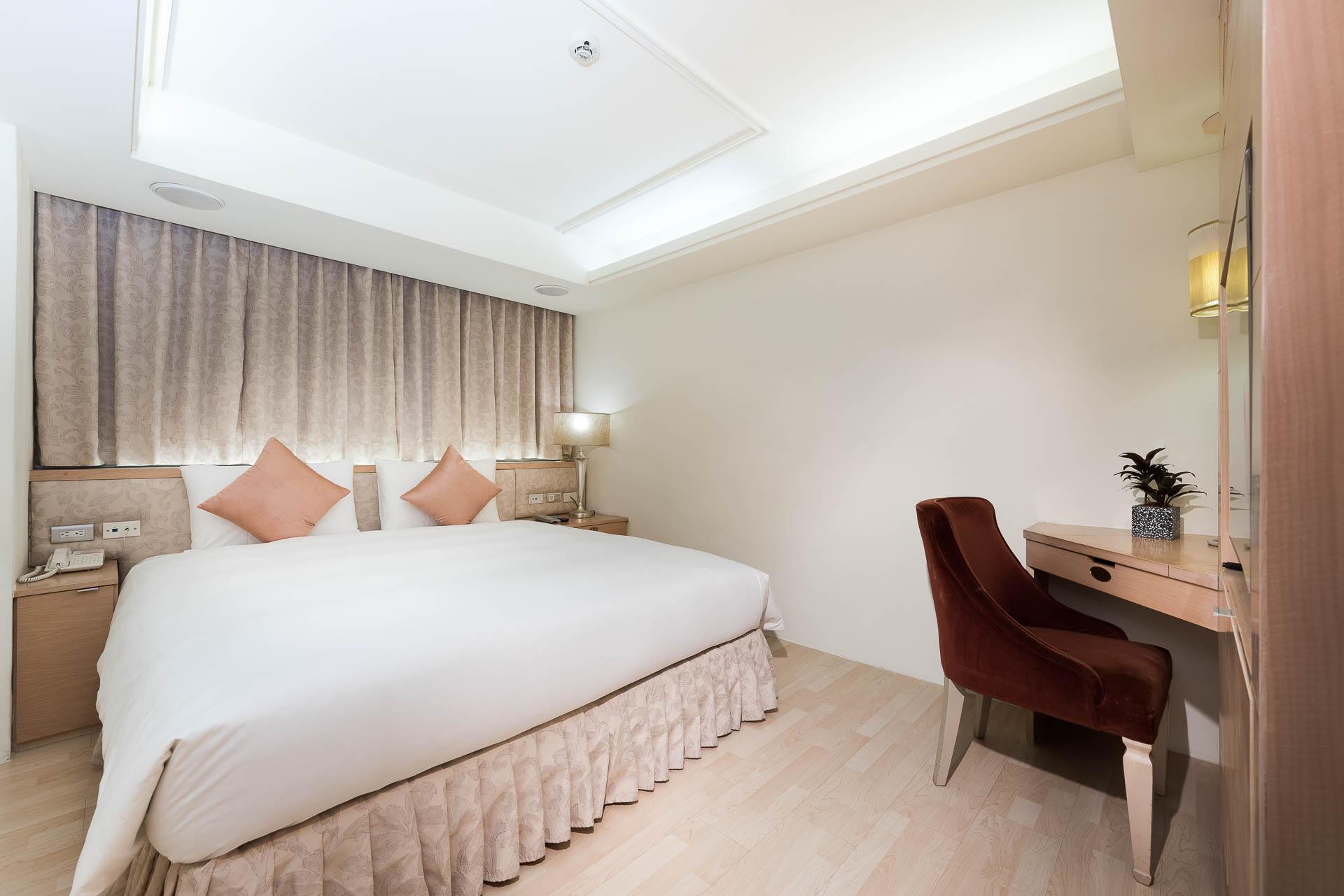 Shin Yuan Celeb Metro Hotel: A room with a large bed, red desk chair and curtains