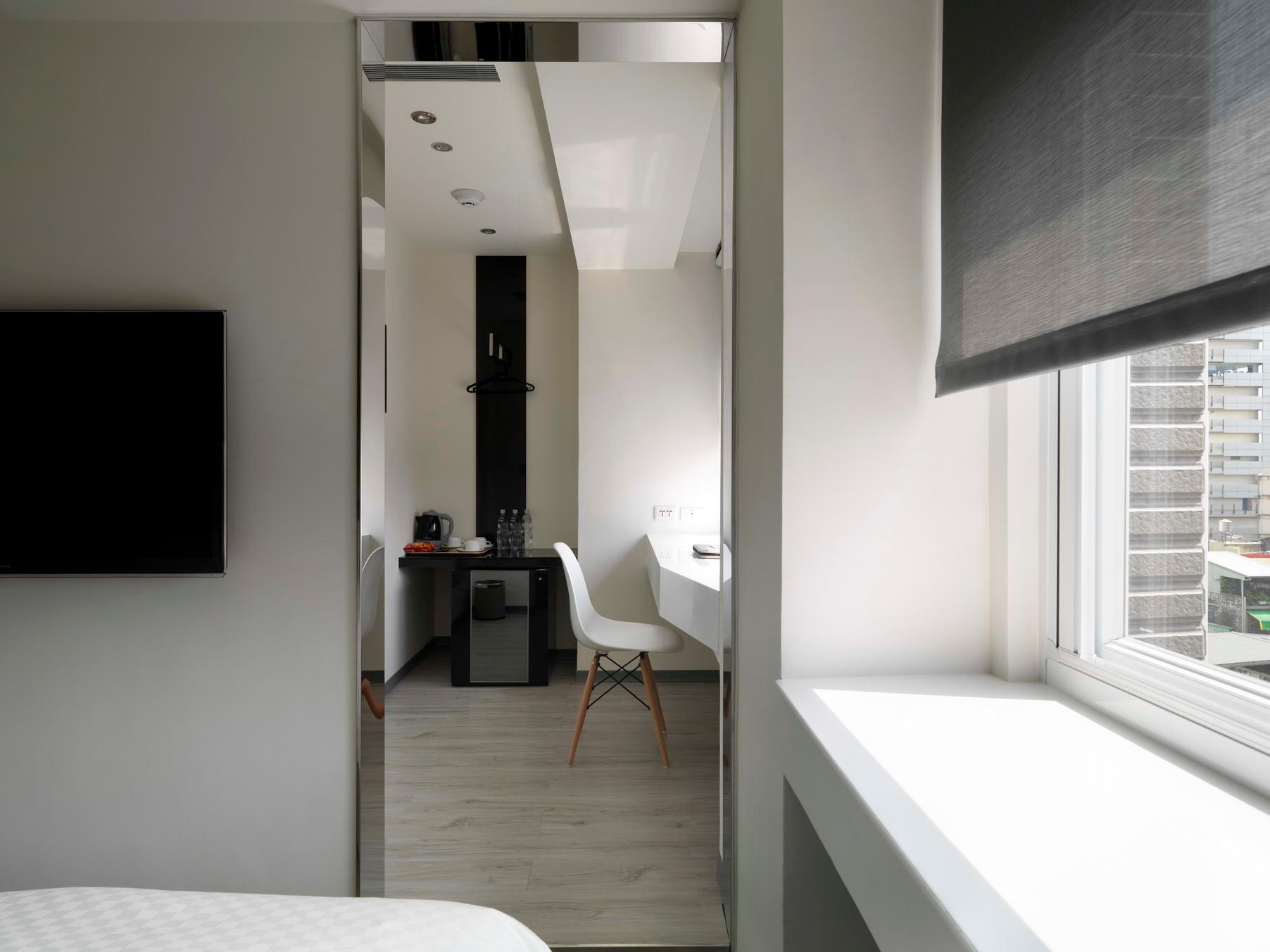 CityInn Plus Taichung Station Branch: 침대 가장자리·책상·거울·창문이 보이는 객실 일부