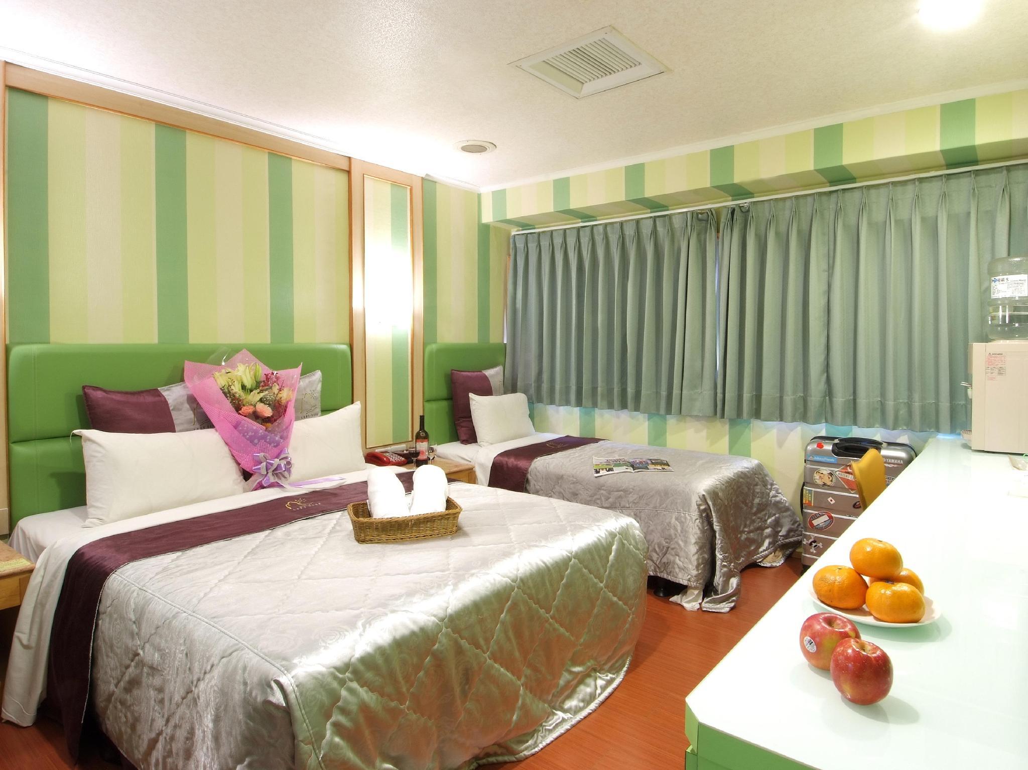 Left Bank Hotel: A room with two beds, a desk and green striped walls