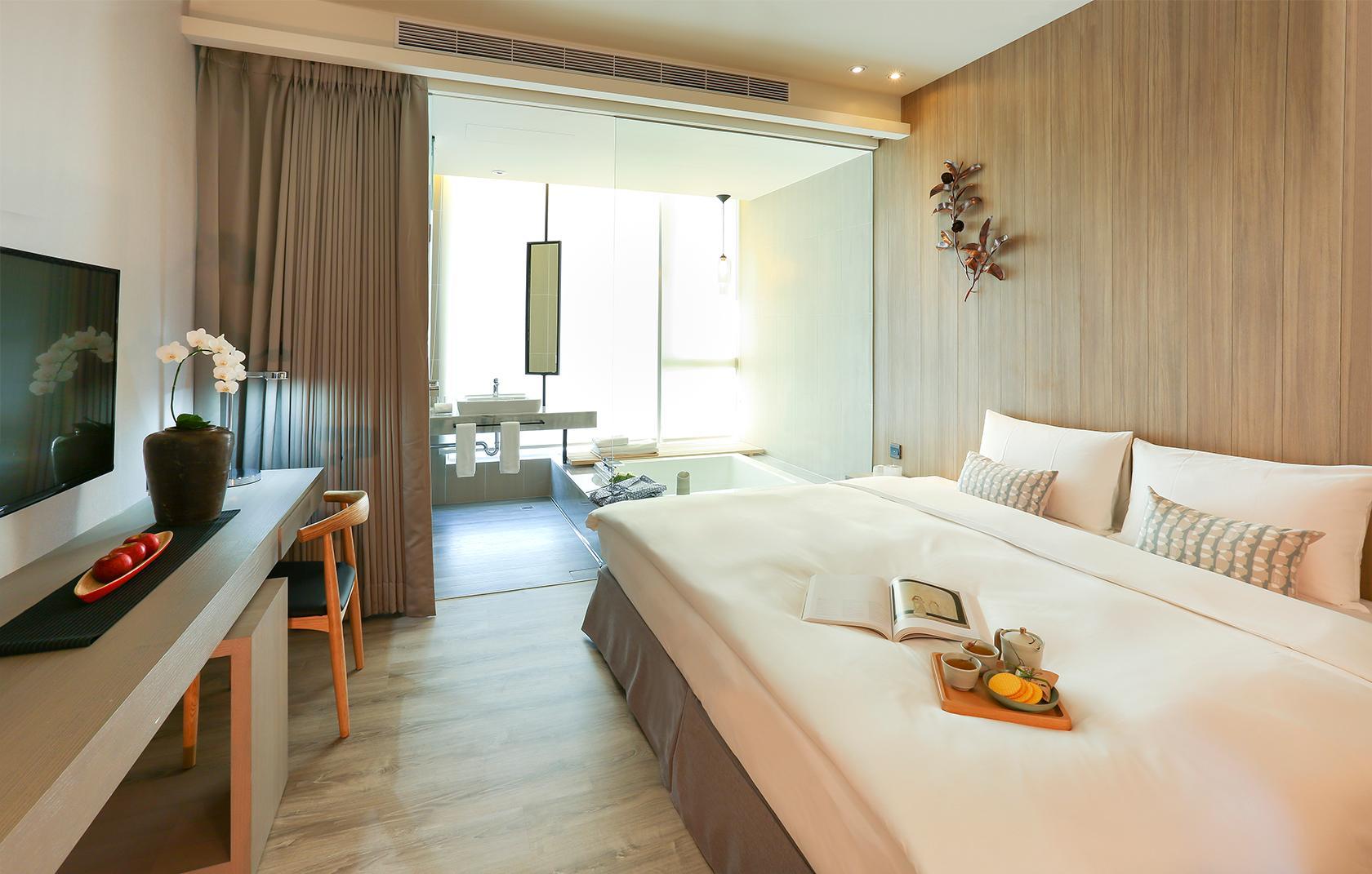 Hotel Day Plus Teascape: A bedroom with a large bed, desk, television, window and tub behind a partition