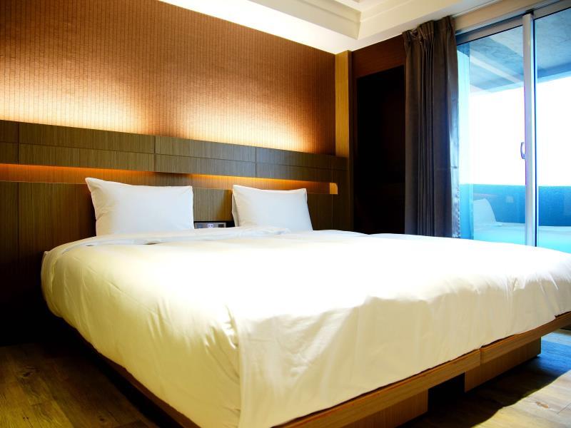 Talmud Hotel Tainan: Guestroom with a double bed, wooden headboard, curtains and glass door