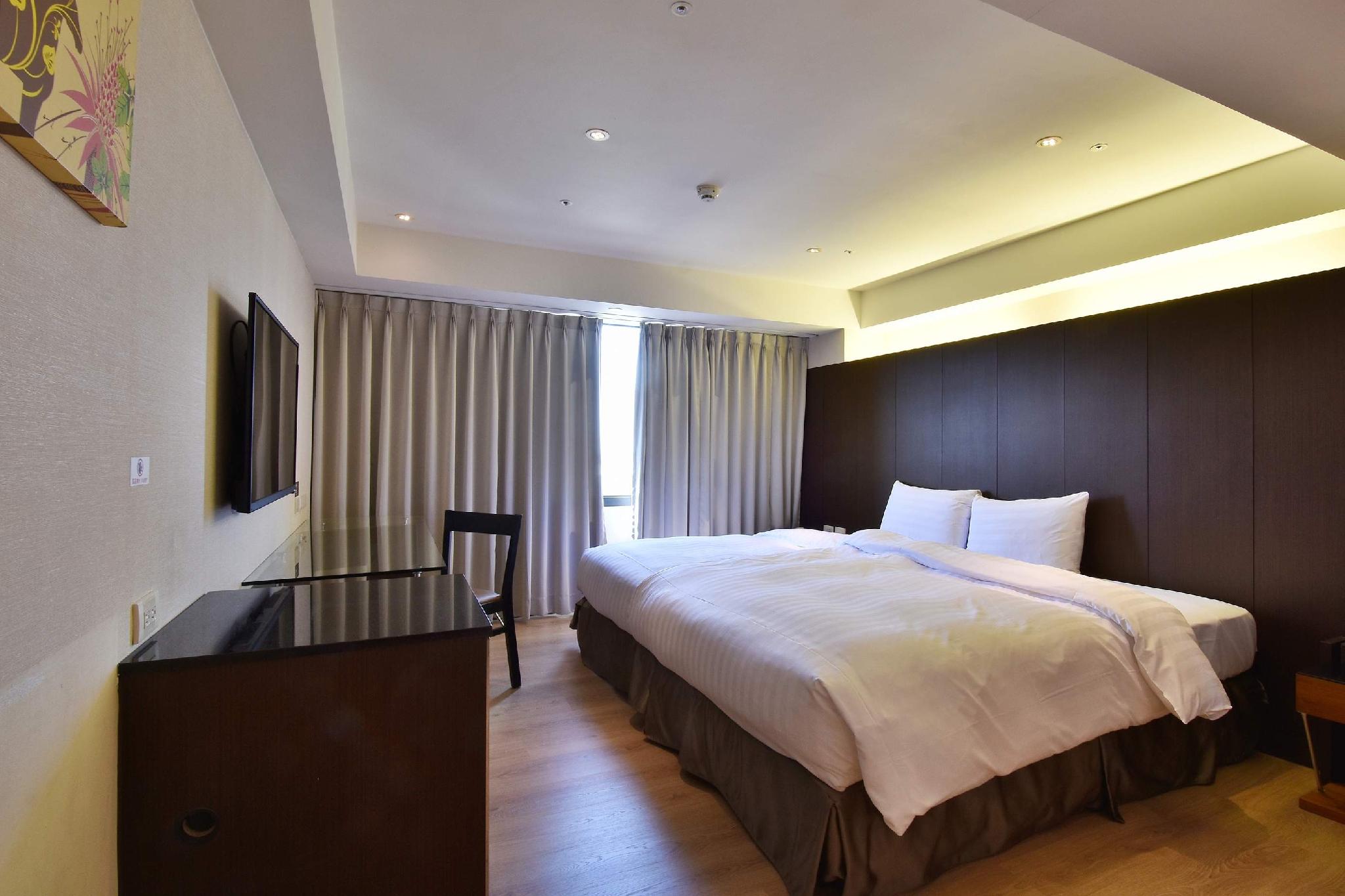 Hotel Hi Chuiyang: A room with a large bed, black desk chair and curtains