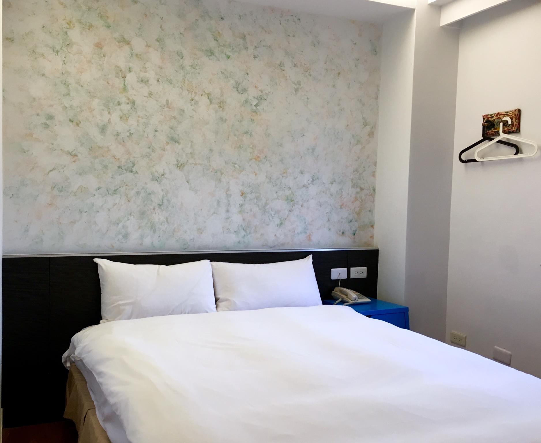 Wantai Hotel: A bedroom with a large bed, blue bedside cabinet, telephone and hanging area