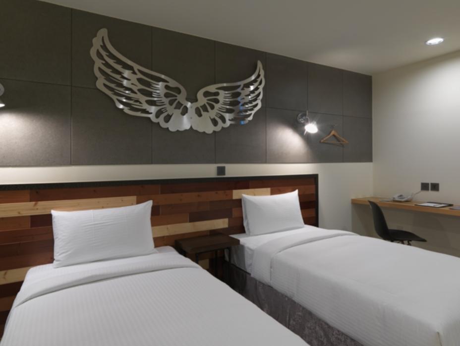 Xinshe Hotel: A room with two single beds, a desk and a wing wall decoration